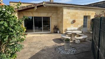 A stone building with a patio, outdoor seating, and a sliding glass door.
