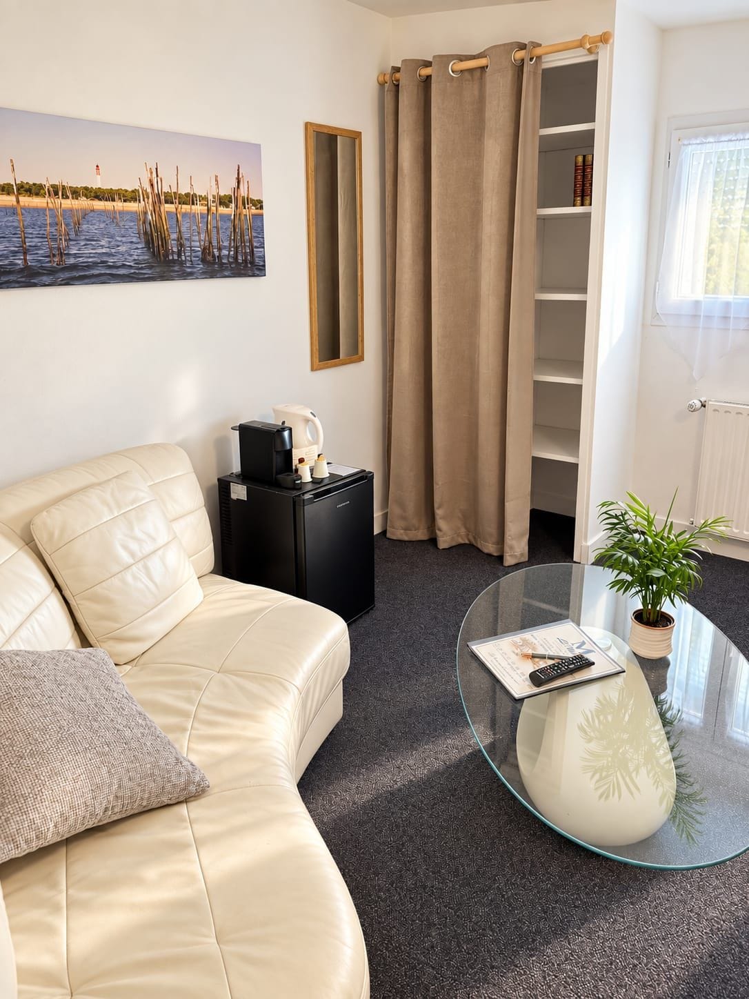 Ein modernes Wohnzimmer mit einer Ledersofa, einem Couchtisch, einem Bücherregal und einem großen Fenster mit Vorhängen.