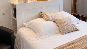 A hotel room with a bed, bedside tables, a lamp, a framed artwork, and a wardrobe.