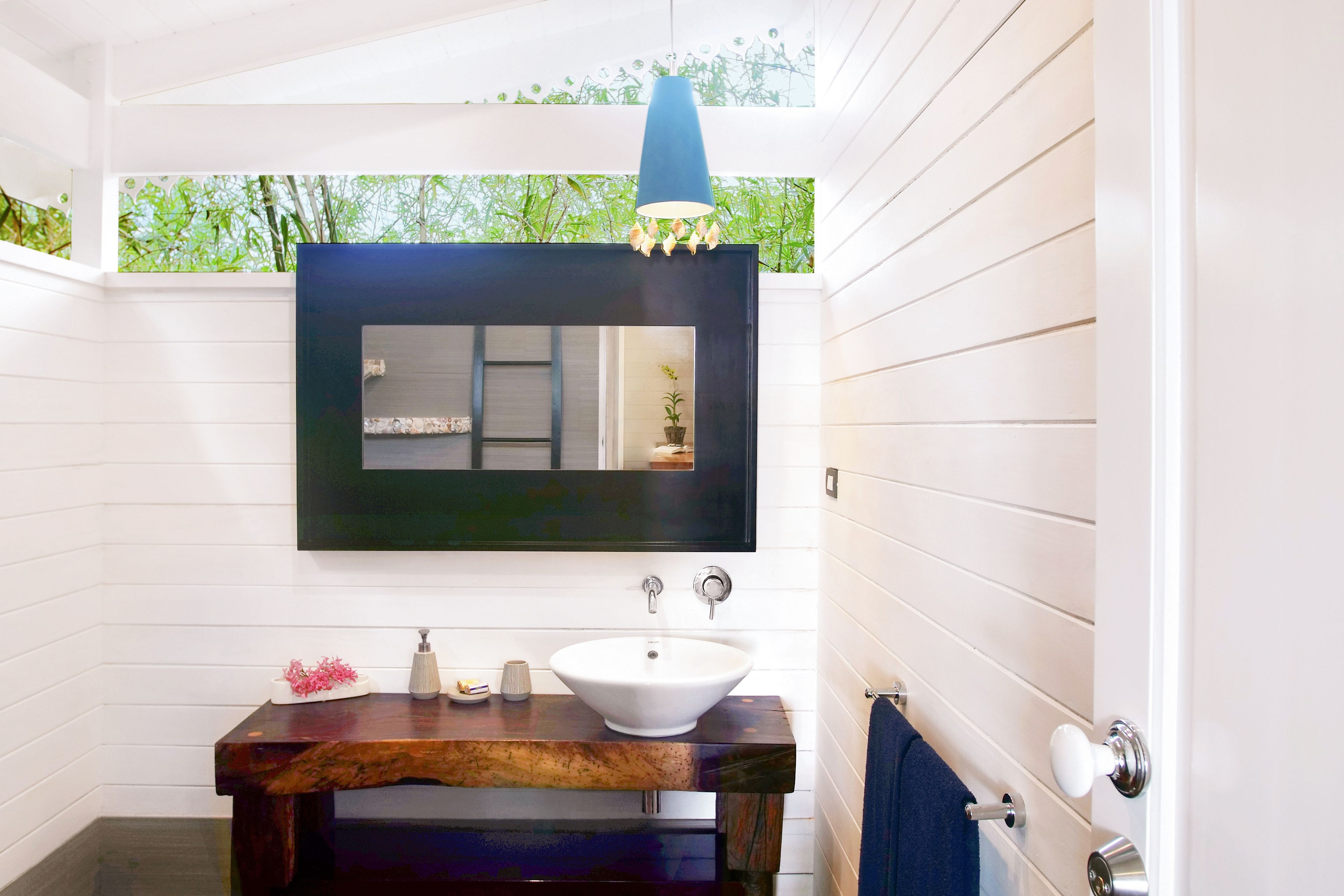 Une salle de bain avec un lavabo blanc, un meuble-lavabo en bois foncé et un grand miroir.