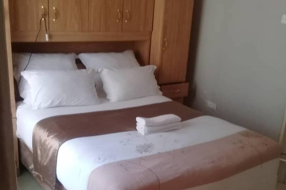 A single-bed room with a wooden headboard, white bedding, and a small bedside table.