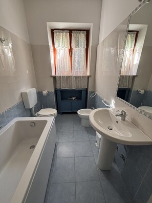 A bathroom with a bathtub, toilet, bidet, and sink.