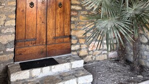A wooden door with metal hinges and a metal latch, set in a stone wall with a stone staircase leading up to it. - Villa Patrizia (Torri del Benaco)
