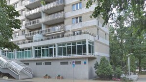 A multi-story building with balconies, a glass facade, and a staircase leading to an upper level.