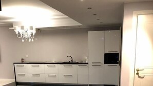 A modern kitchen with a glass island, white cabinetry, and a chandelier.