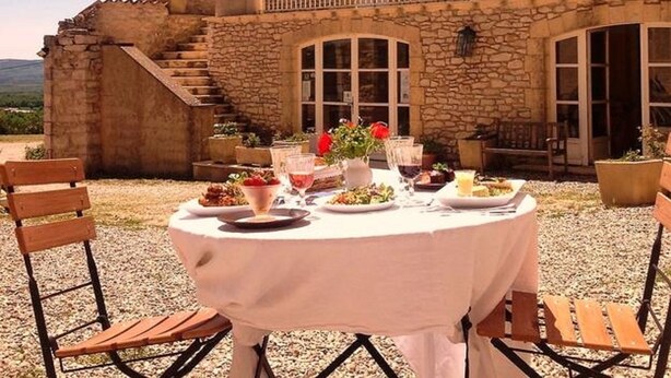 Un edificio de piedra con un balcón y una mesa lista para comer al aire libre.