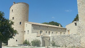 Un edificio de piedra con una torre redonda, varias ventanas y un muro de piedra.