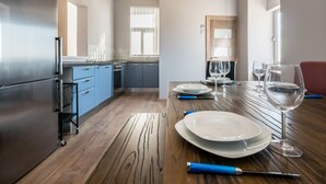 Eine moderne Küche mit einem Holztisch, gedeckt für das Essen, mit einem Edelstahlkühlschrank, blauen Schränken und einer Holzaussparung an der Decke.