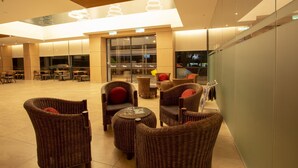 A spacious lobby with wicker furniture, a glass wall, and a modern ceiling design. - AZ Hotel & Serviced Apartments (Labuan)