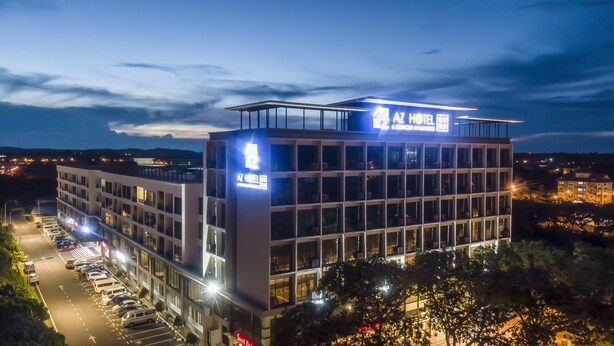 A modern hotel building with a prominent sign, multiple floors, and a parking lot. - AZ Hotel & Serviced Apartments (Labuan)