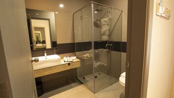 Un baño moderno con ducha de vidrio, tocador con espejo e inodoro.