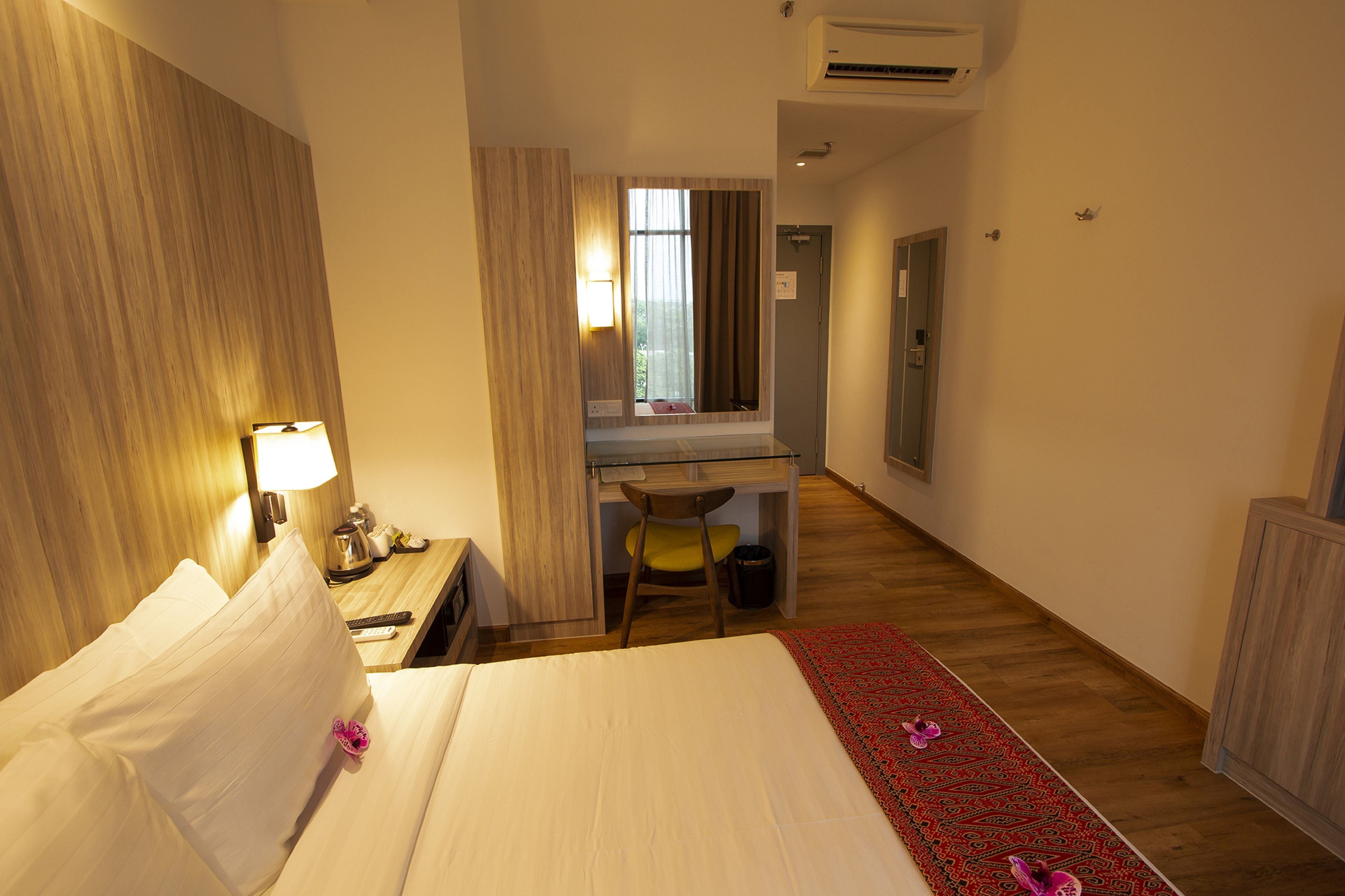Una camera d'albergo con un letto, una scrivania, una sedia e una finestra con tende.