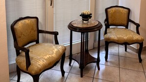 Ein Zimmer mit drei Stühlen, einem kleinen Tisch, einer Tür mit Milchglasfenster und einem Fliesenboden.