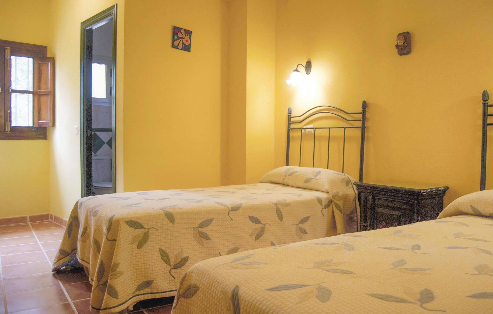 A room with two beds, a wooden headboard, a wall-mounted light, and a small decorative item.