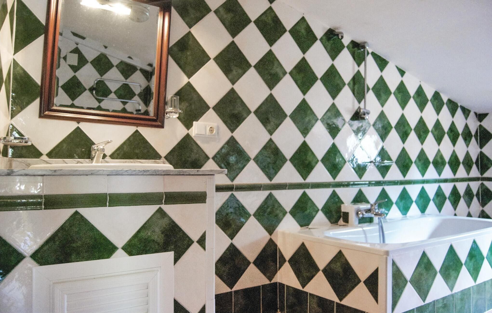 A bathroom with a diamond-patterned tile wall, a white sink, and a bathtub.