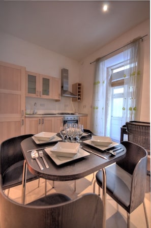 Una cocina moderna con armarios de madera, una mesa de comedor para cuatro personas y un amplio ventanal con cortinas.