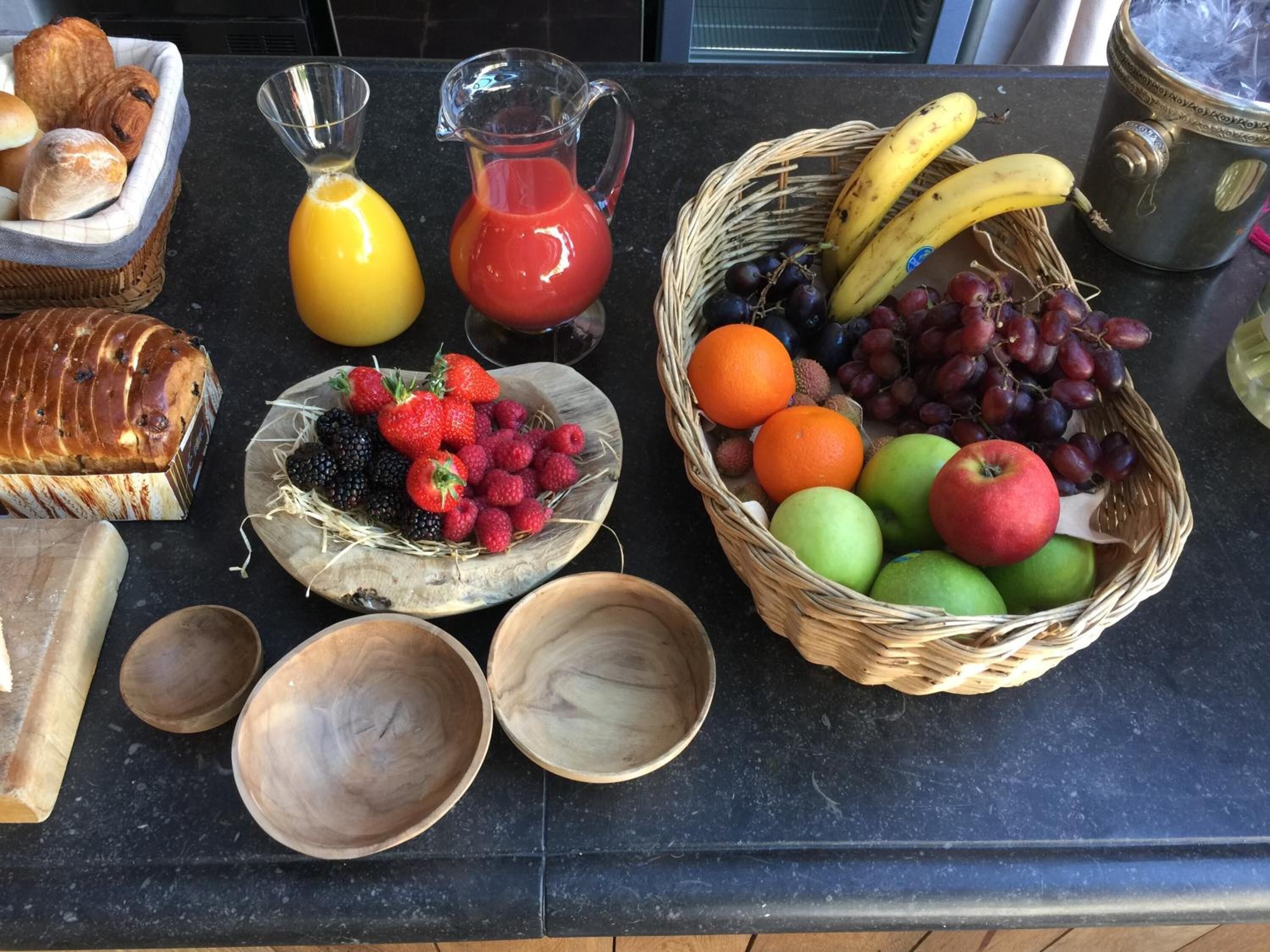 Una encimera de cocina con diversos alimentos, incluyendo pan, frutas y una hogaza de pan horneado.