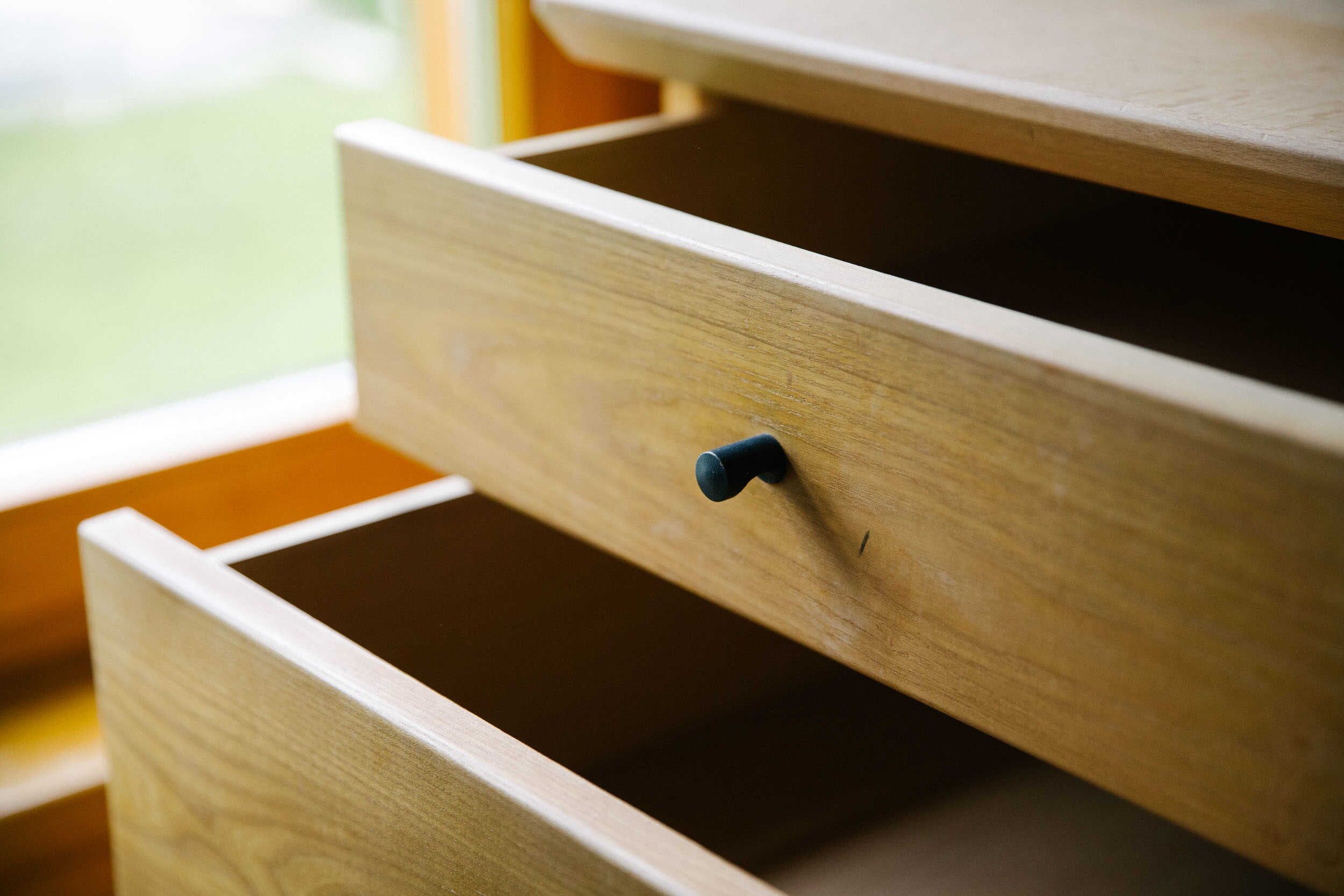 A wooden drawer with a black knob, part of a piece of furniture.