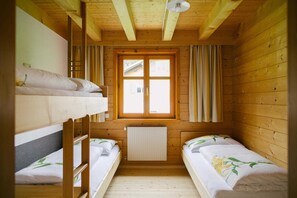 Una cabaña de madera con dos literas, una ventana con cortinas y un radiador.