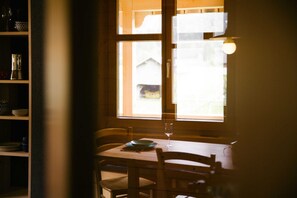 Comedor con mesa, sillas, un vaso y ventana con vistas.
