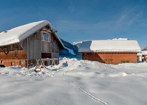 Paisaje nevado con un granero de madera y un edificio de ladrillo.
