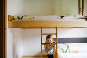 Un llit superposat amb una escala, una llitera inferior amb un coixí i una paret amb un mirall.