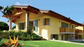A modern two-story house with a sloped roof, large windows, and a balcony.