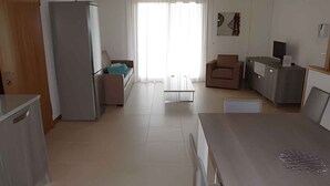 A modern kitchen with a refrigerator, a dining table, and a sofa.