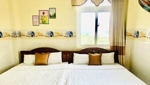 A neatly made bed with a wooden headboard, white bedding, and decorative pillows. - Dinh Sa Ly Son Hotel (Ly Son)