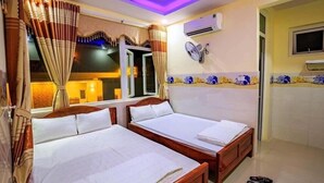 A hotel room with two wooden beds, a window with curtains, an air conditioning unit, and a wall-mounted fan. - Dinh Sa Ly Son Hotel (Ly Son)