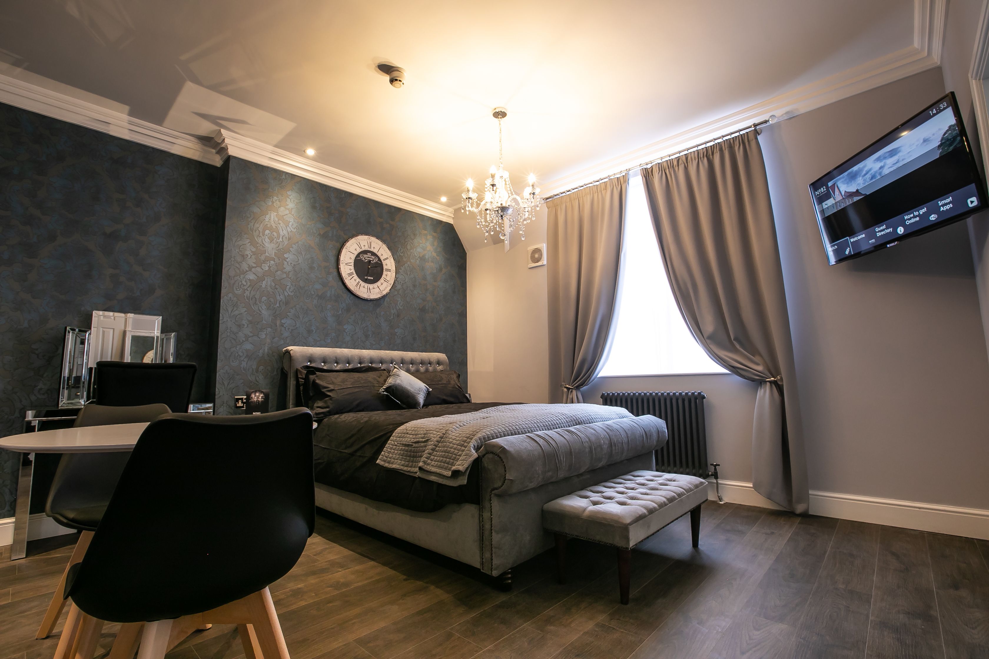 Un dormitorio moderno con cama, escritorio y televisor montado en la pared.
