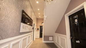 A hallway with patterned wallpaper, a chandelier, and a black door with the number 82. - Number 82 The Unthank (Norwich)