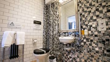 A bathroom with a tiled wall, a sink, a toilet, and a towel rack.