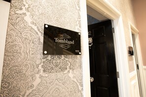 A sign with the name "Tombland" and a number "N082" on a wall with a patterned wallpaper.