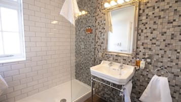 Et badeværelse med et hvidt badekar, en vask med et spejl over, og et bruseområde.