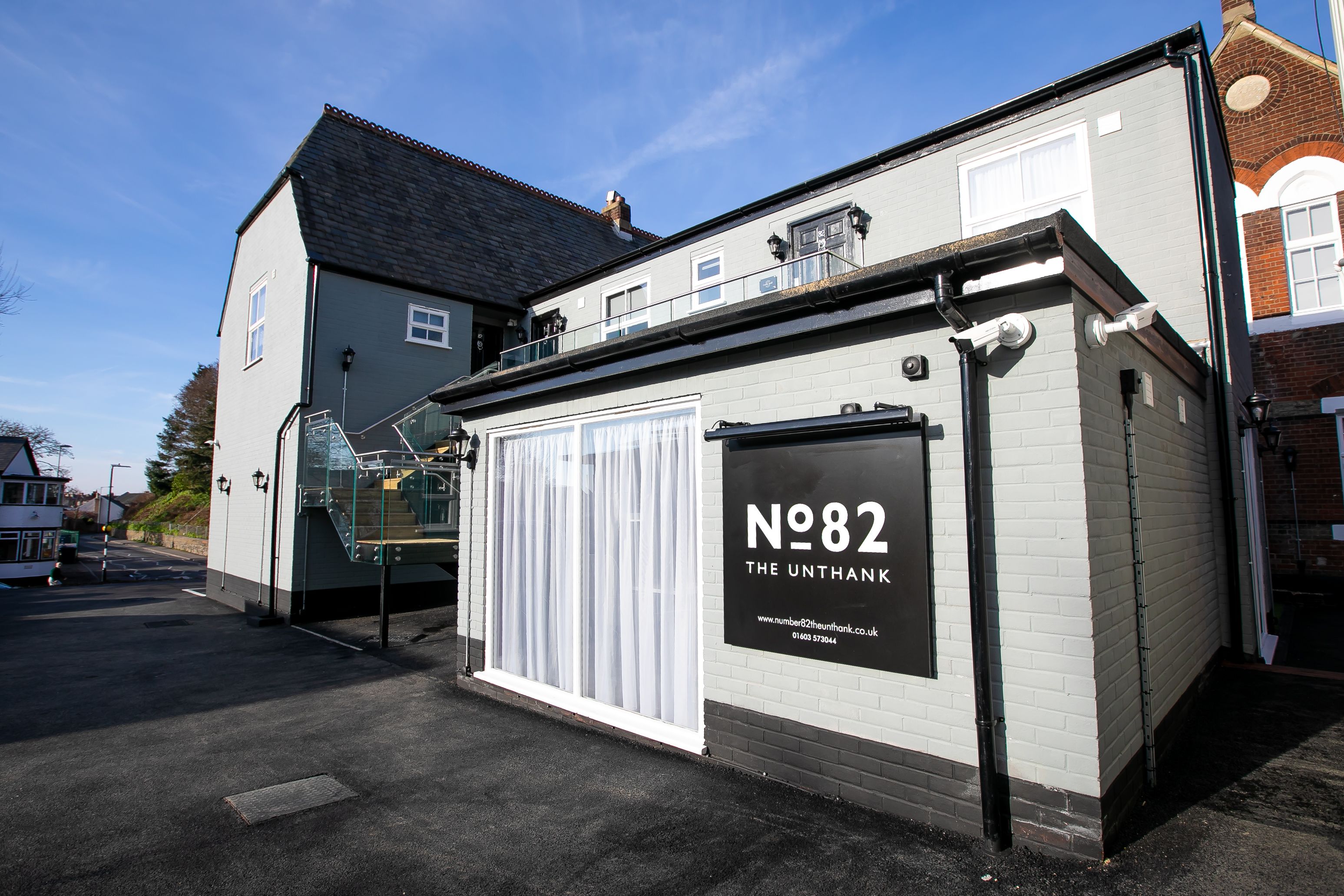 A building with a sign reading "N82 The Unthank" and a staircase leading to an upper level.