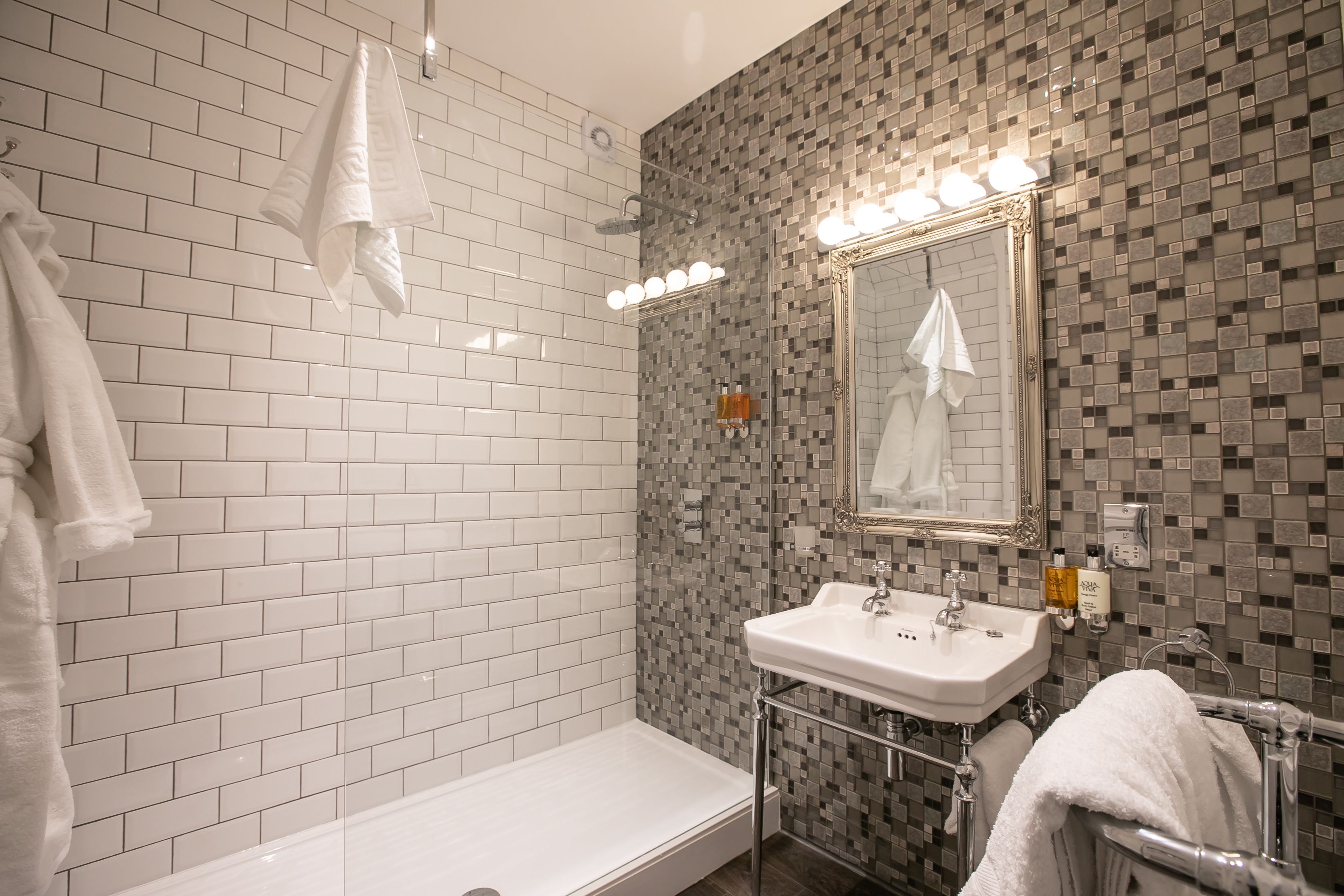 A modern bathroom with a white bathtub, a sink with a mirror, and a shower area.
