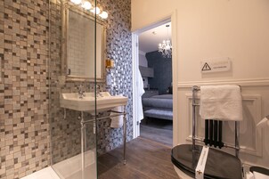 Un baño moderno con pared de mosaicos, cabina de ducha de cristal, lavabo y perchero para toallas.