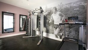 A gym with a treadmill, weight machines, and a large mirror. - Number 82 The Unthank (Norwich)