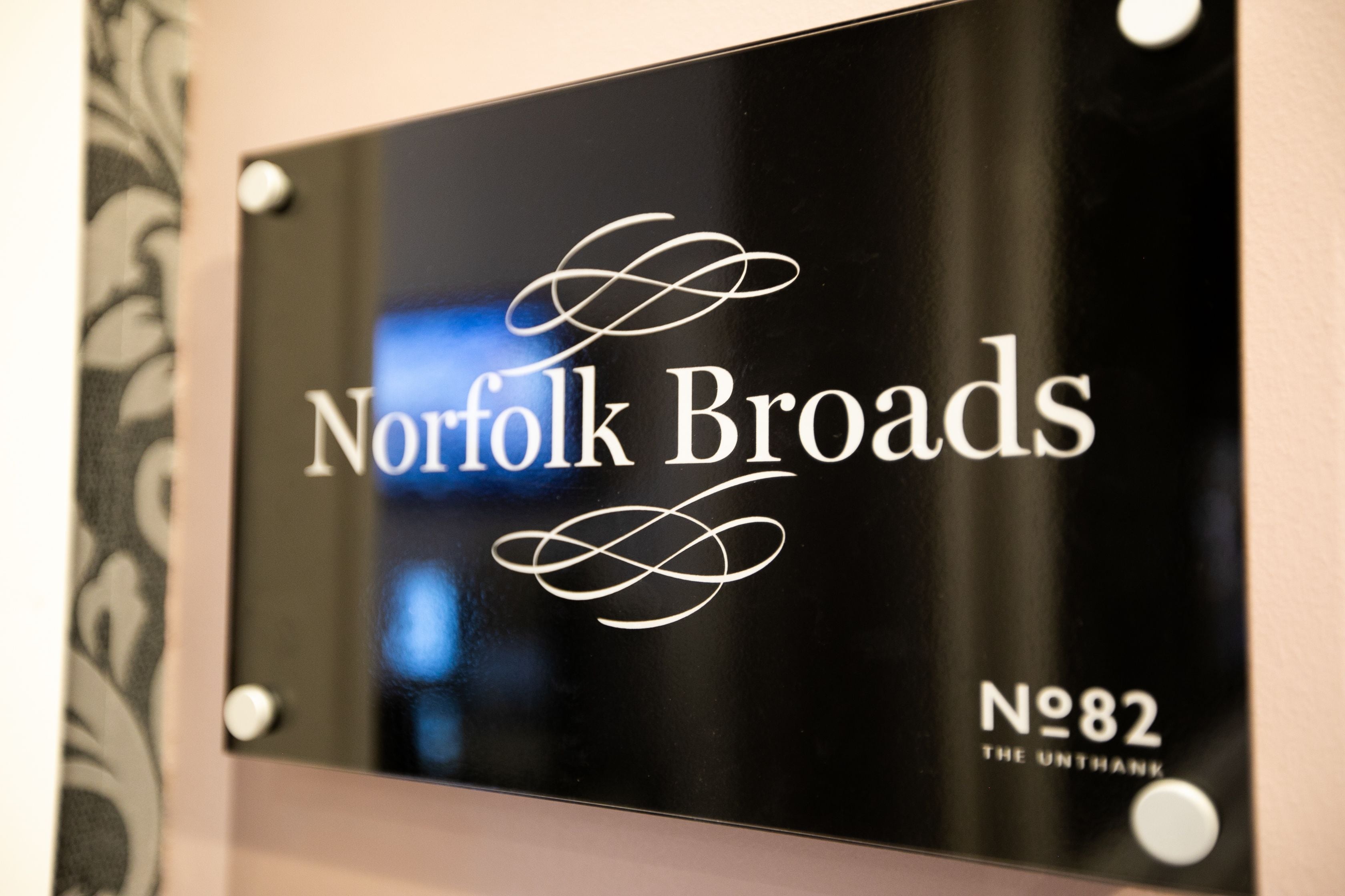 Une pancarte portant l’inscription « Norfolk Broads » et « N82 The Untank », indiquant un lieu ou le nom d’une propriété.