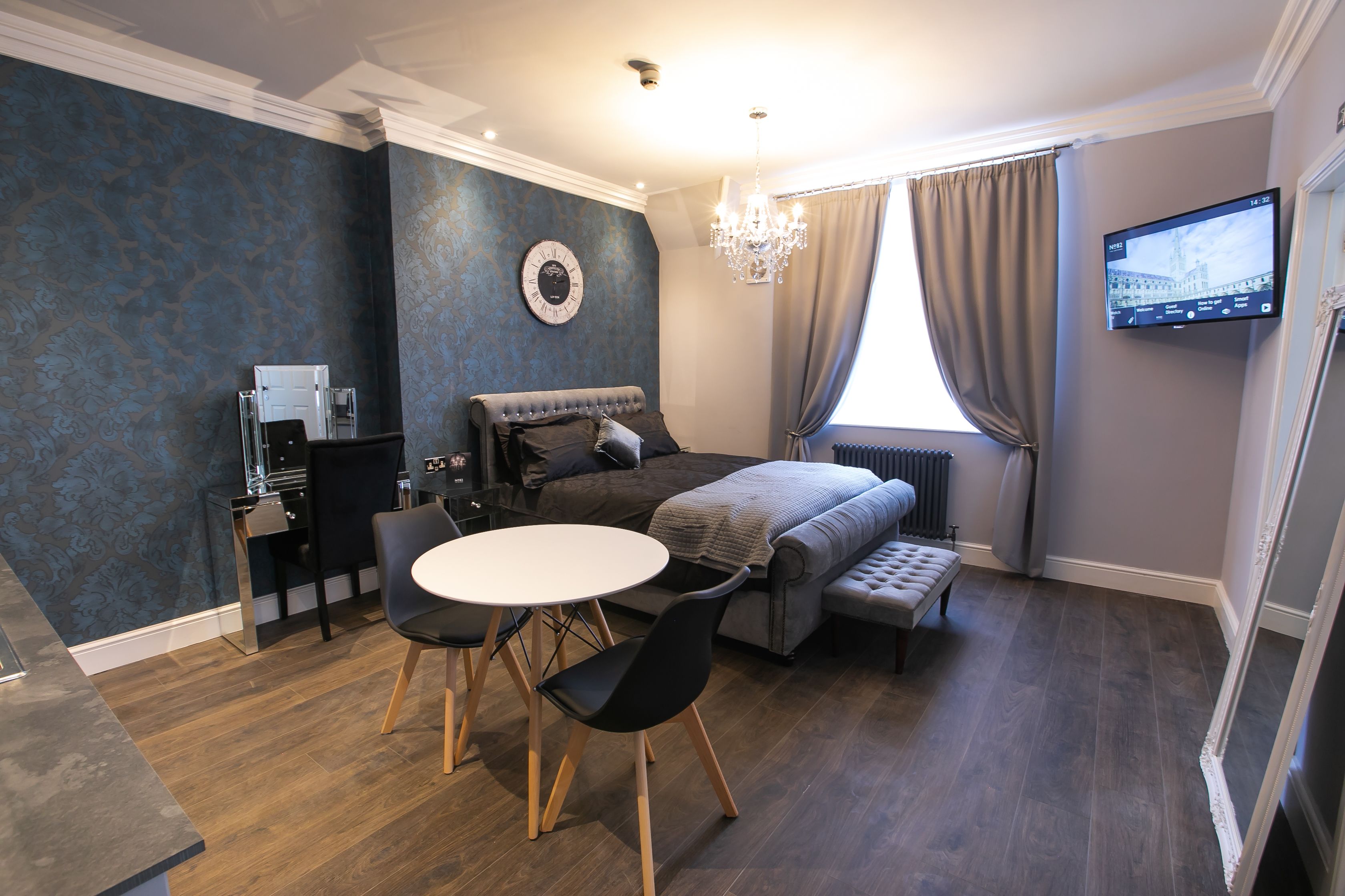A modern bedroom with a bed, bedside table, and a TV mounted on the wall.
