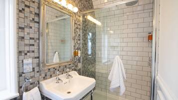 A bathroom with a tiled shower, a sink with a mirror, and a towel rack.