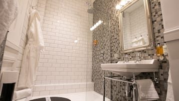 A bathroom with a white bathtub, a sink with a mirror above it, and a shower area with a tiled wall.