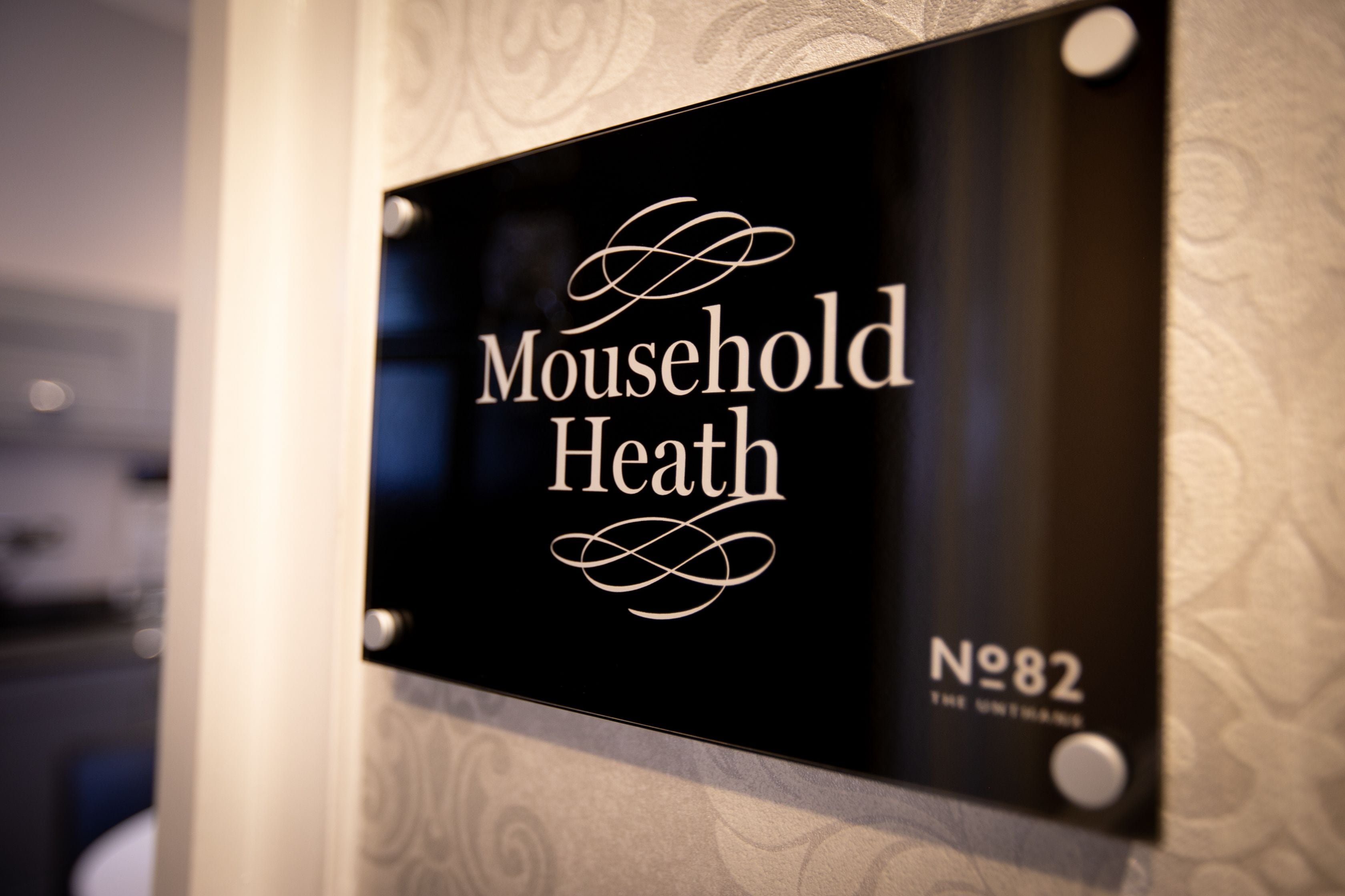 A sign with the text 'Mousehold Heath' and 'No 82' indicating a location or room number.