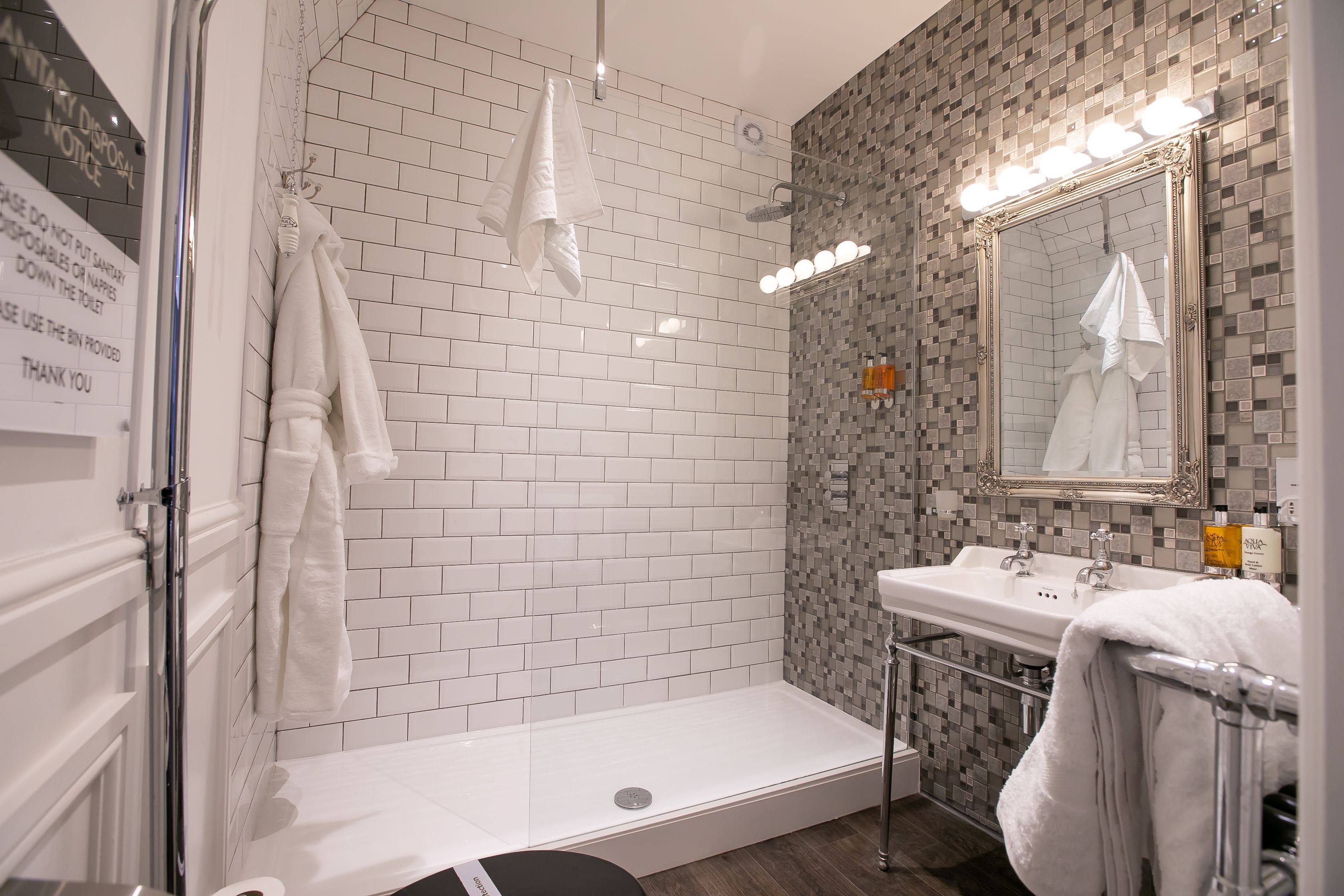 Un baño moderno con ducha, lavabo y espejo con iluminación.