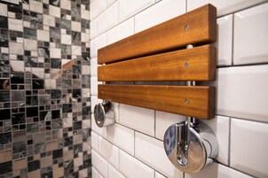 A bathroom with a wooden bench mounted on the wall, a mirror, and a tiled floor.