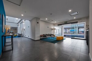Un moderno vestíbulo de hotel con una zona de estar, una recepción y un amplio ventanal con vistas a la calle.