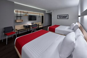 Une chambre d’hôtel avec deux lits, un bureau, une chaise, une télévision et un tableau encadré au mur.