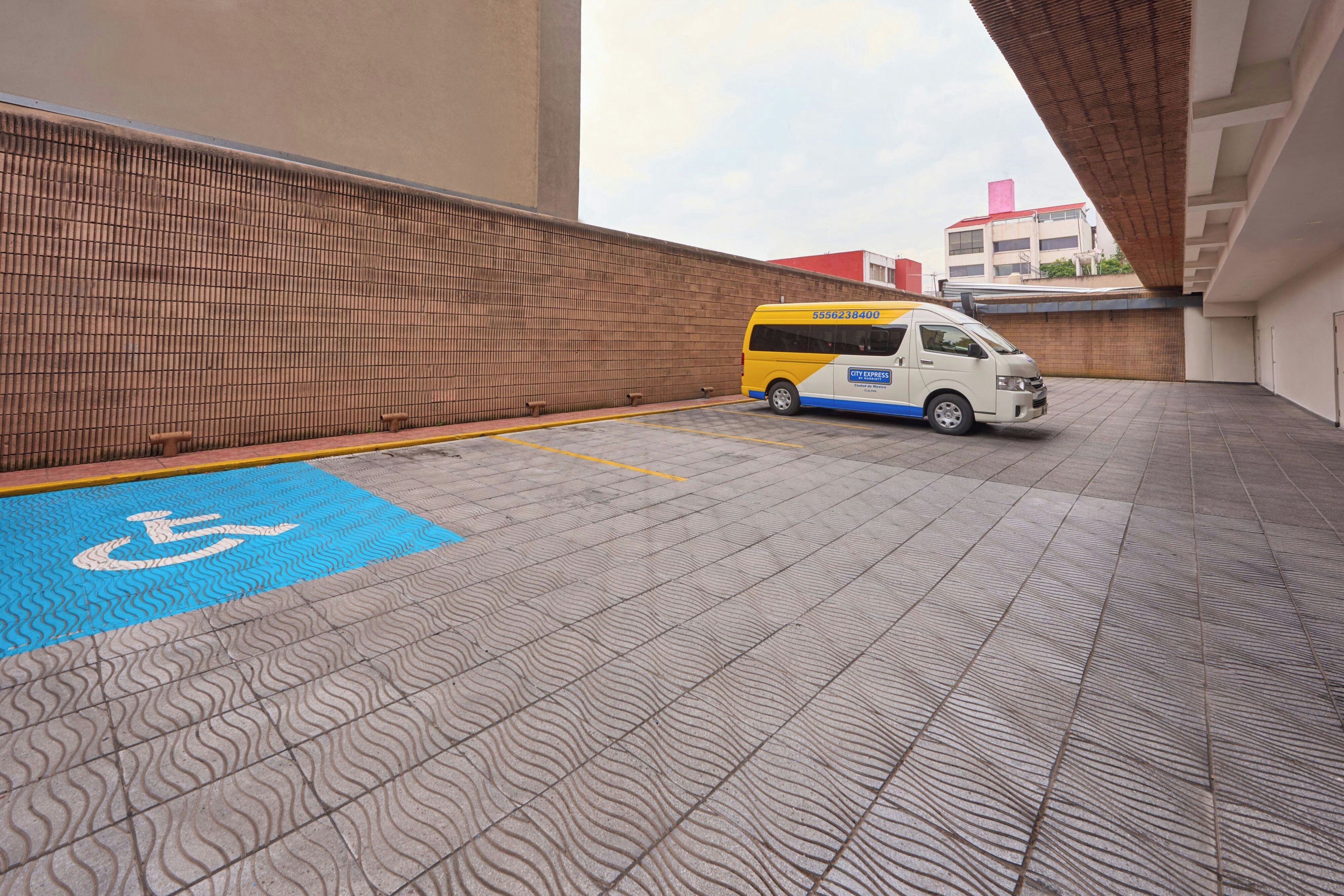 A parking area with a wheelchair-accessible space marked by blue tiles and a white wheelchair symbol.