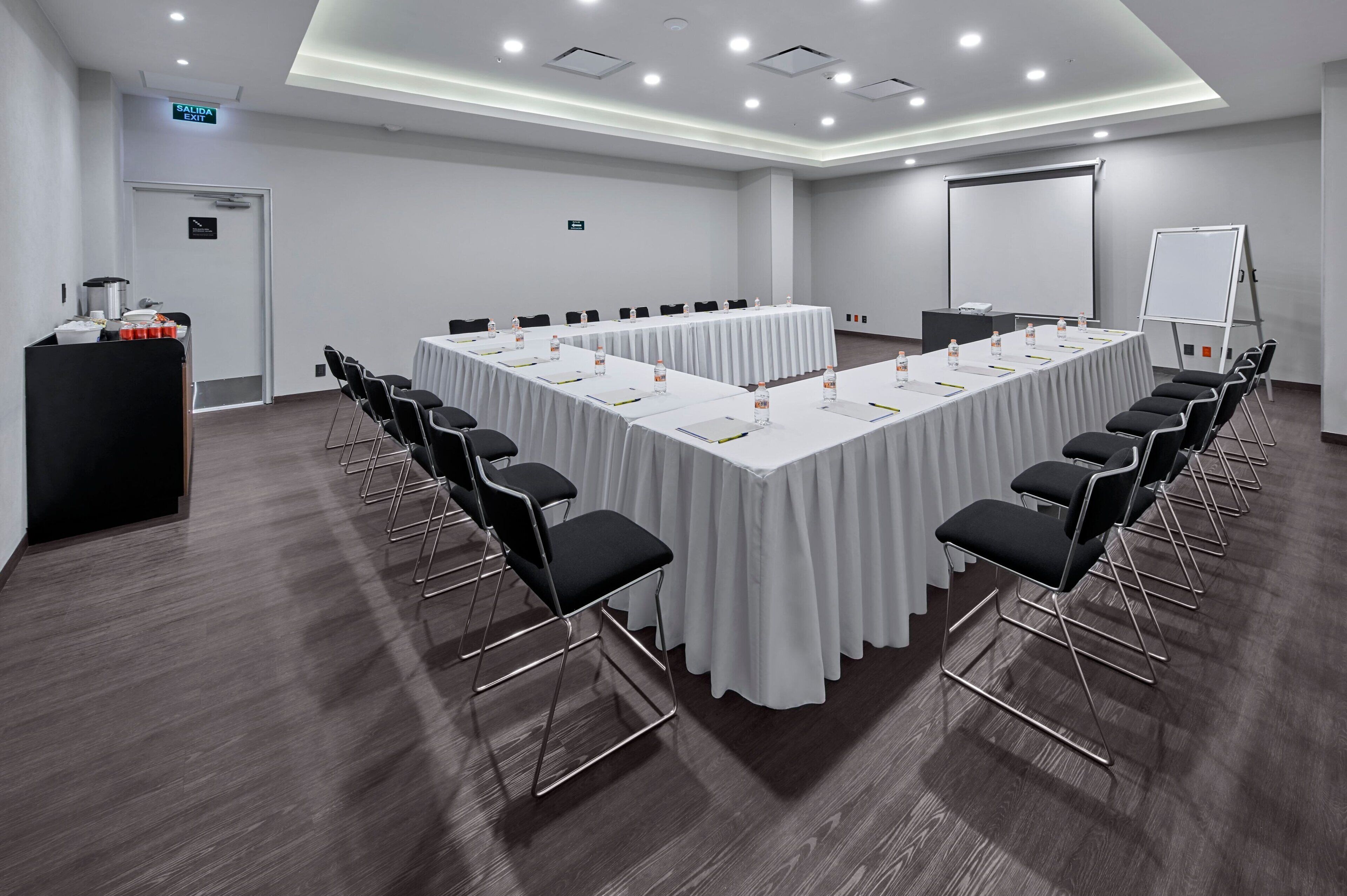A conference room with a long table, chairs, a projector screen, and a whiteboard.